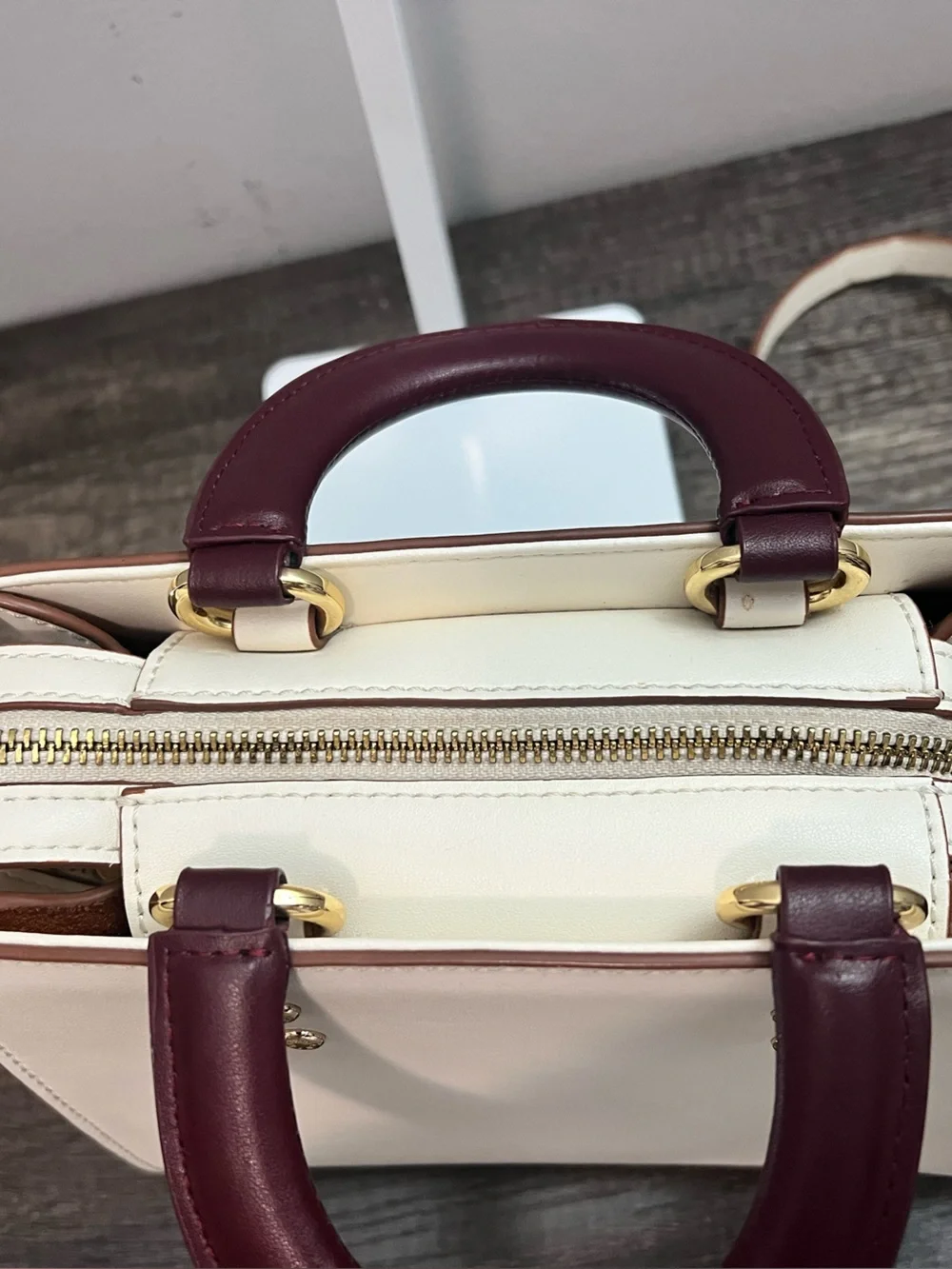 Cream Leather with contrasting plum handles and goldtone hardware crossbody.